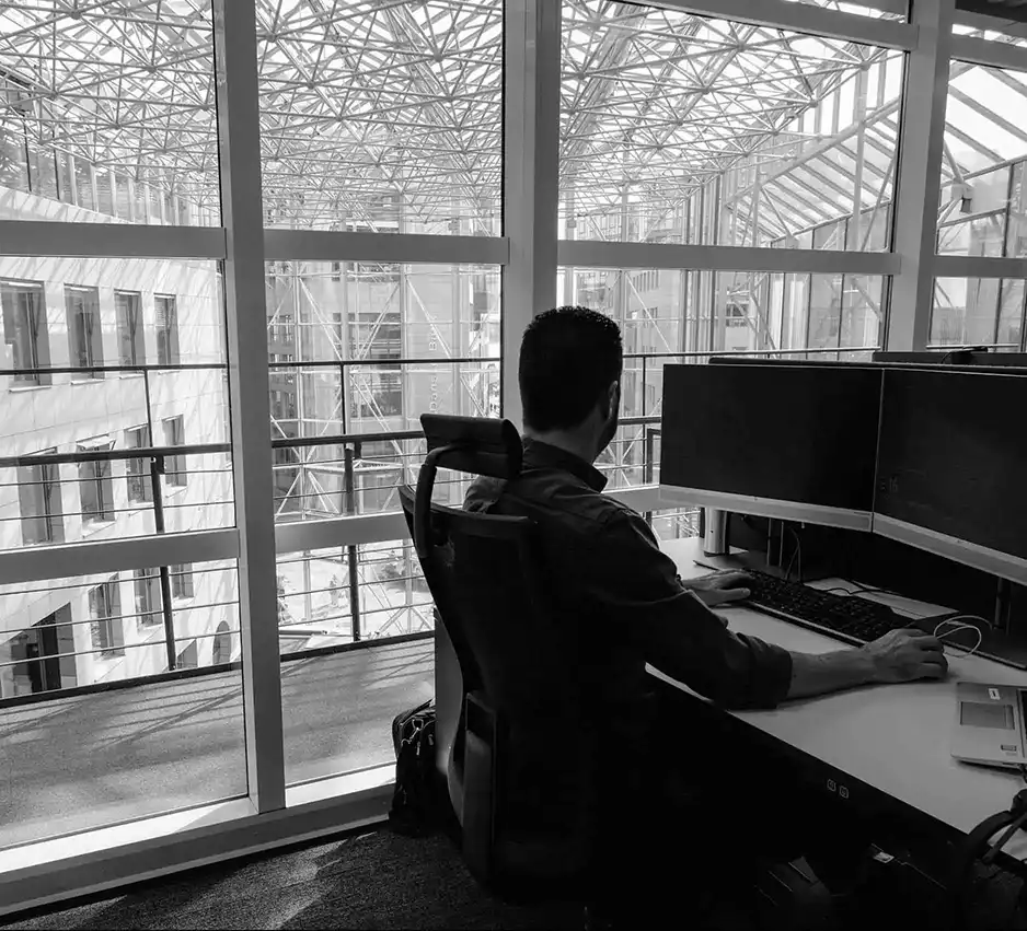 Mann sitter foran 2 skjermer