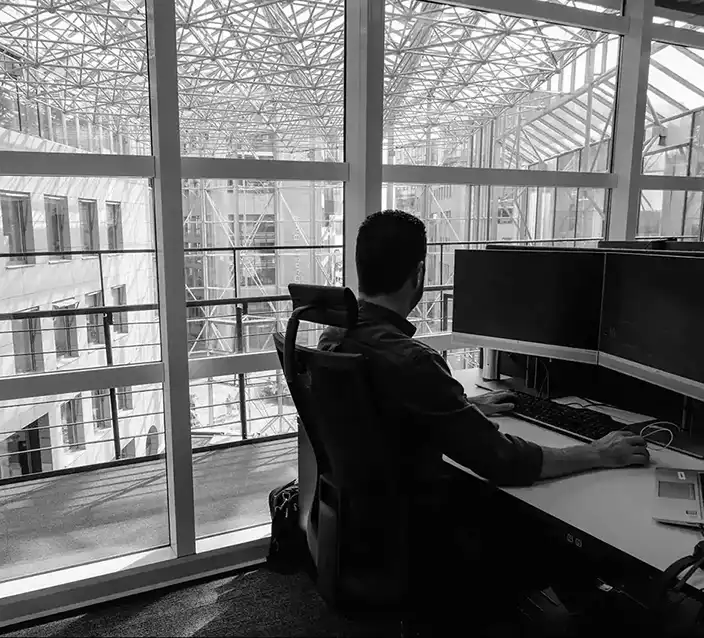 Mann sitter foran 2 skjermer